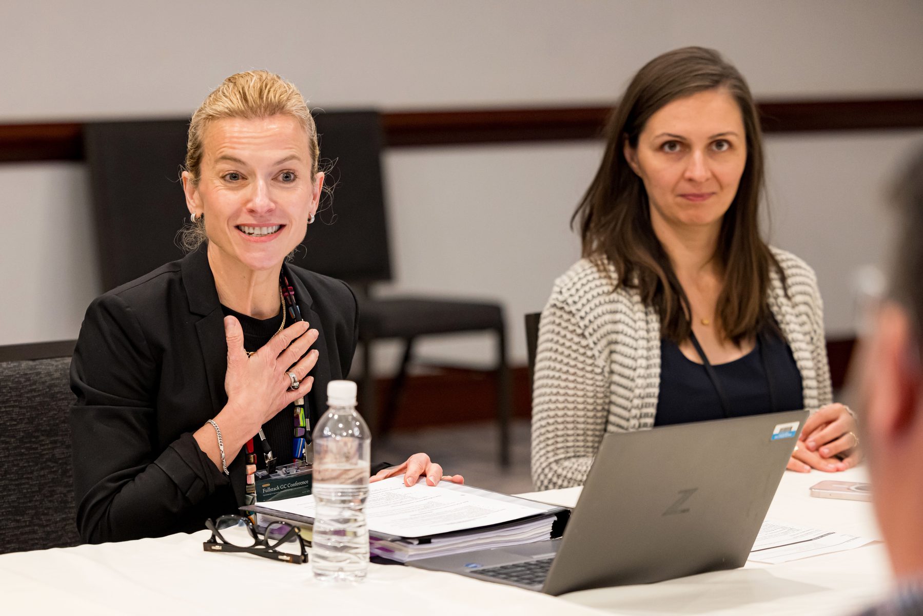Two women engaged in conversation at a roundtable discussion.