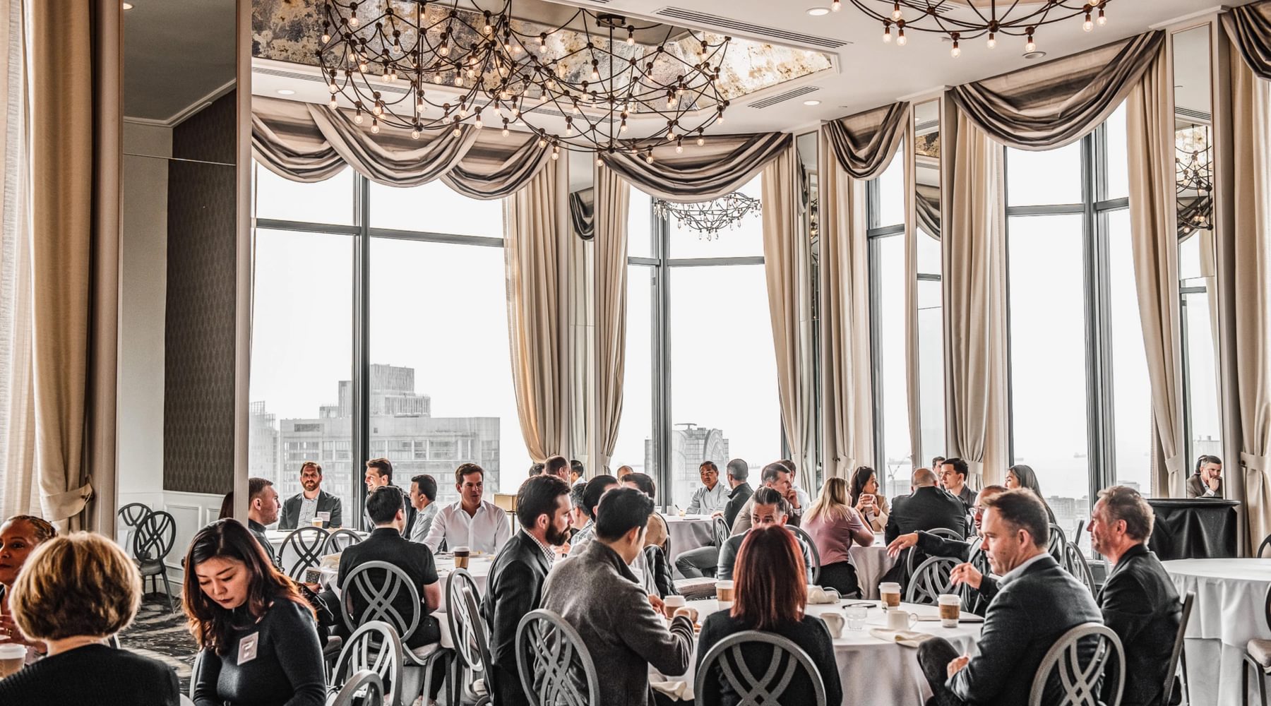 Ballroom full of people sitting down around tables.